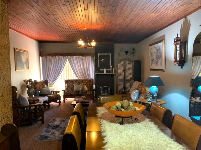 Spacious open-plan living and dining area featuring a warm timber-clad ceiling and a built-in fireplace, offering a cozy and traditional atmosphere.
