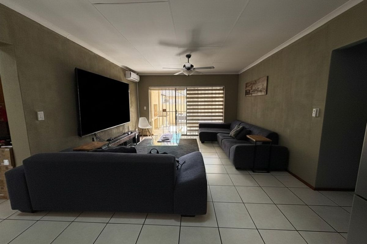 Spacious living room featuring tiled flooring, a ceiling fan, and a split-system air conditioner, with direct access to an outdoor area via sliding glass doors.