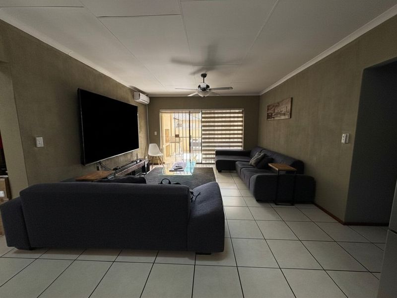 Spacious living room featuring tiled flooring, a ceiling fan, and a split-system air conditioner, with direct access to an outdoor area via sliding glass doors.