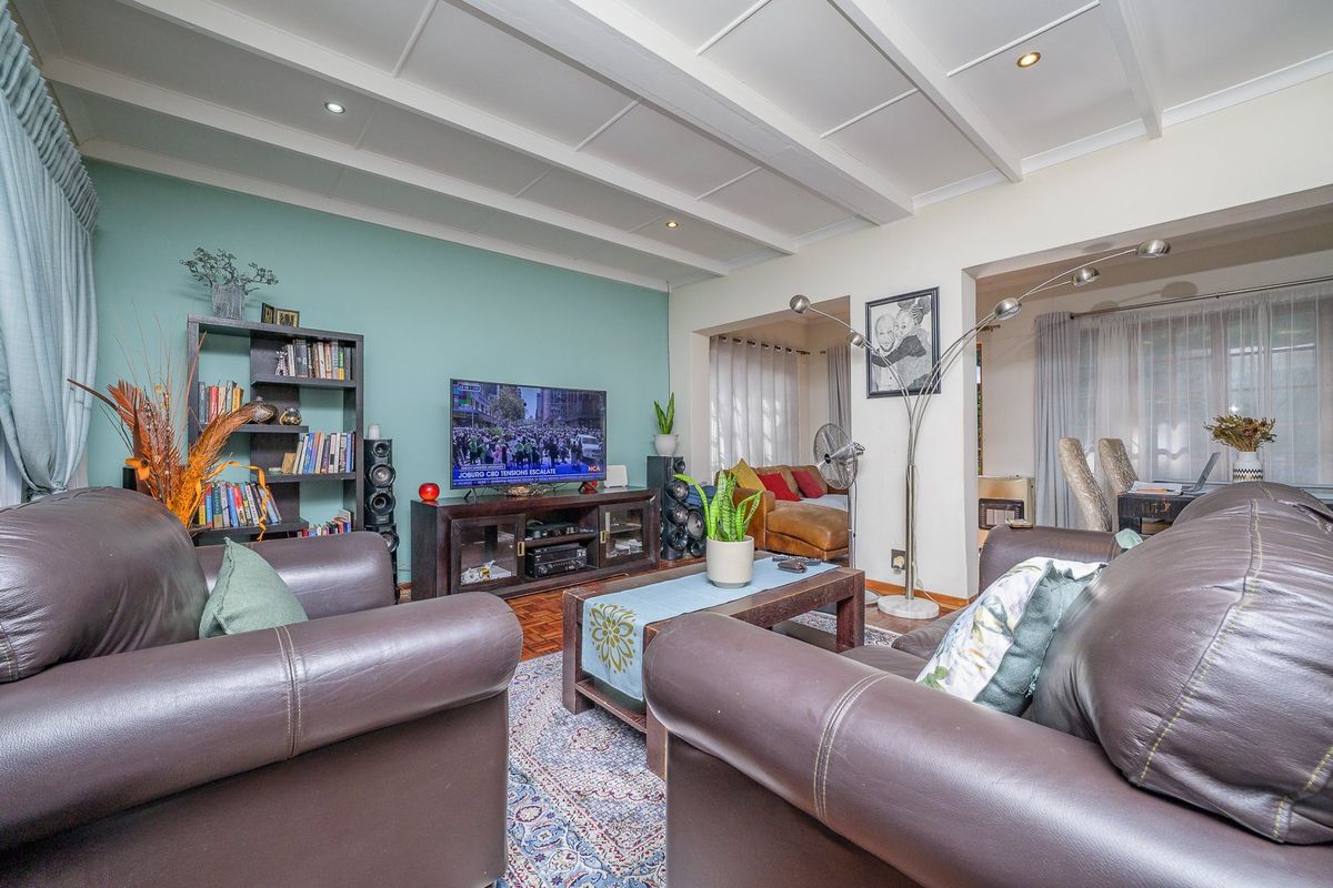 Spacious living room featuring a distinctive coffered ceiling, recessed lighting, and warm parquet flooring, creating a comfortable and inviting atmosphere.