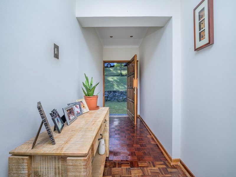 A bright entrance hall featuring classic parquet flooring and a solid timber door leading to the exterior garden area.