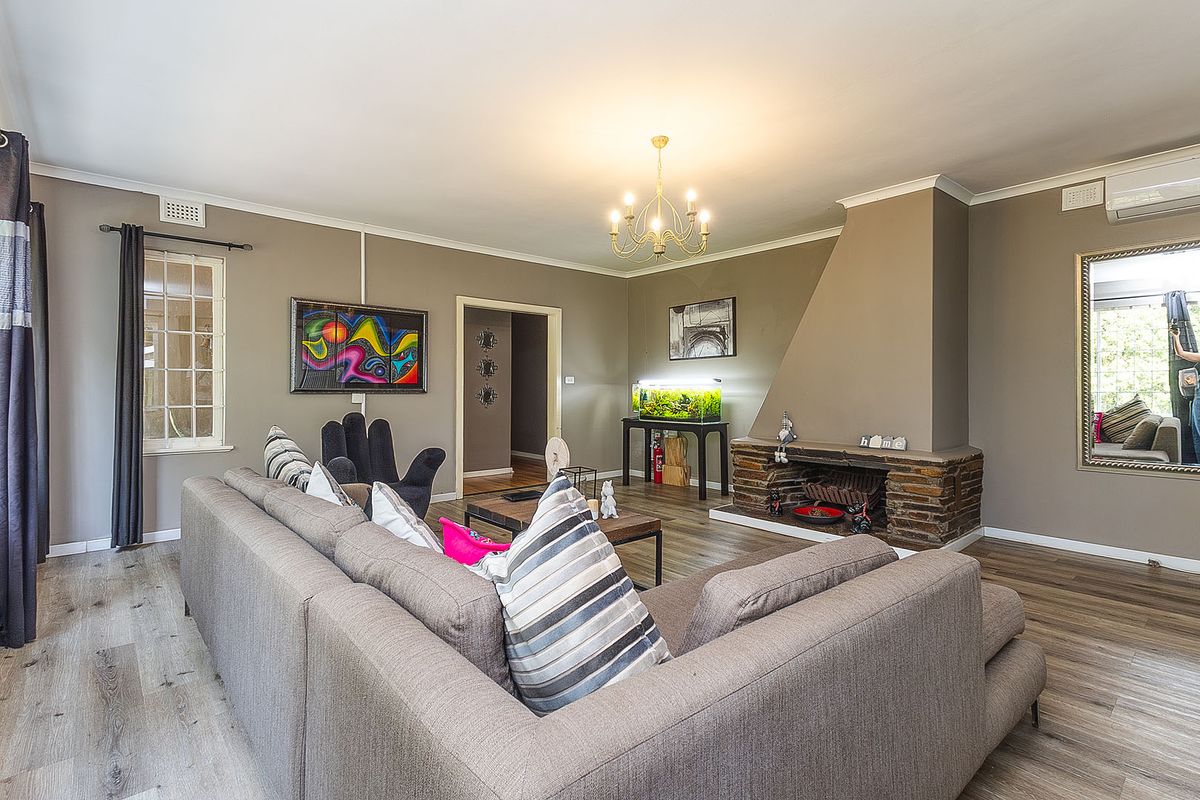 A comfortable living room featuring a stone fireplace, laminate flooring, and an air conditioning unit, creating a warm and inviting atmosphere.