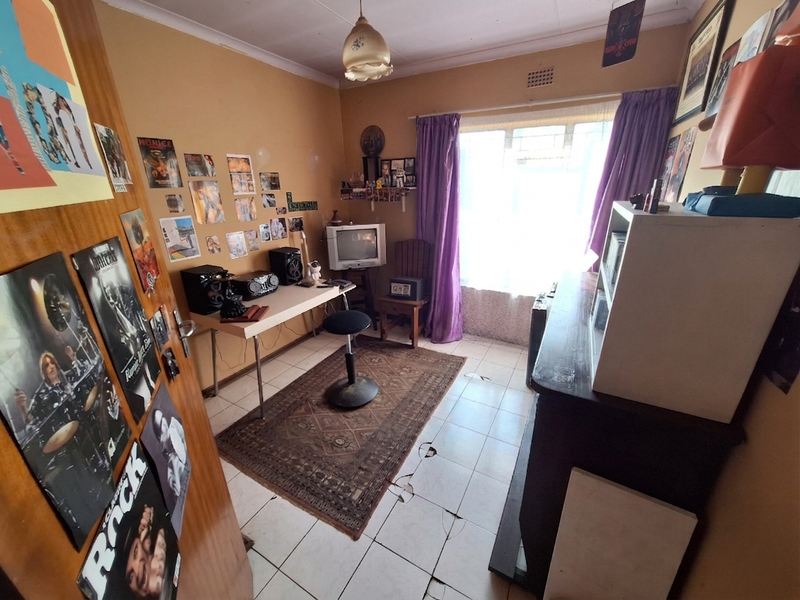 A bedroom featuring tiled flooring and a window with security bars, currently requiring maintenance due to damaged floor tiles.