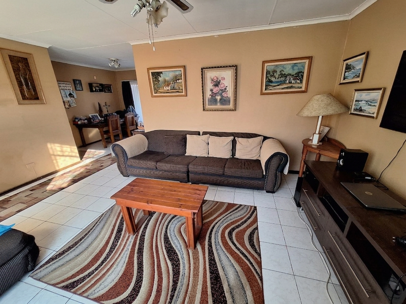 A living room featuring tiled flooring and a ceiling fan, offering a functional space with neutral wall tones.