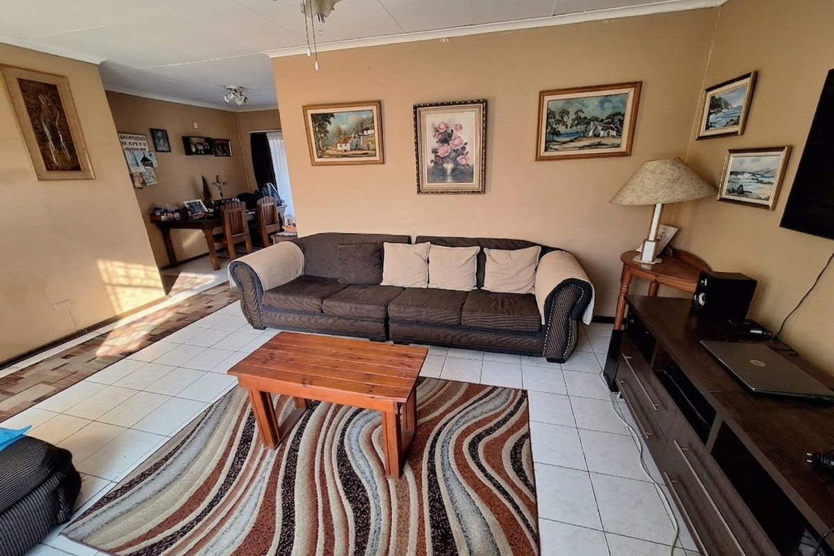 A living room featuring tiled flooring and a ceiling fan, offering a functional space with neutral wall tones.