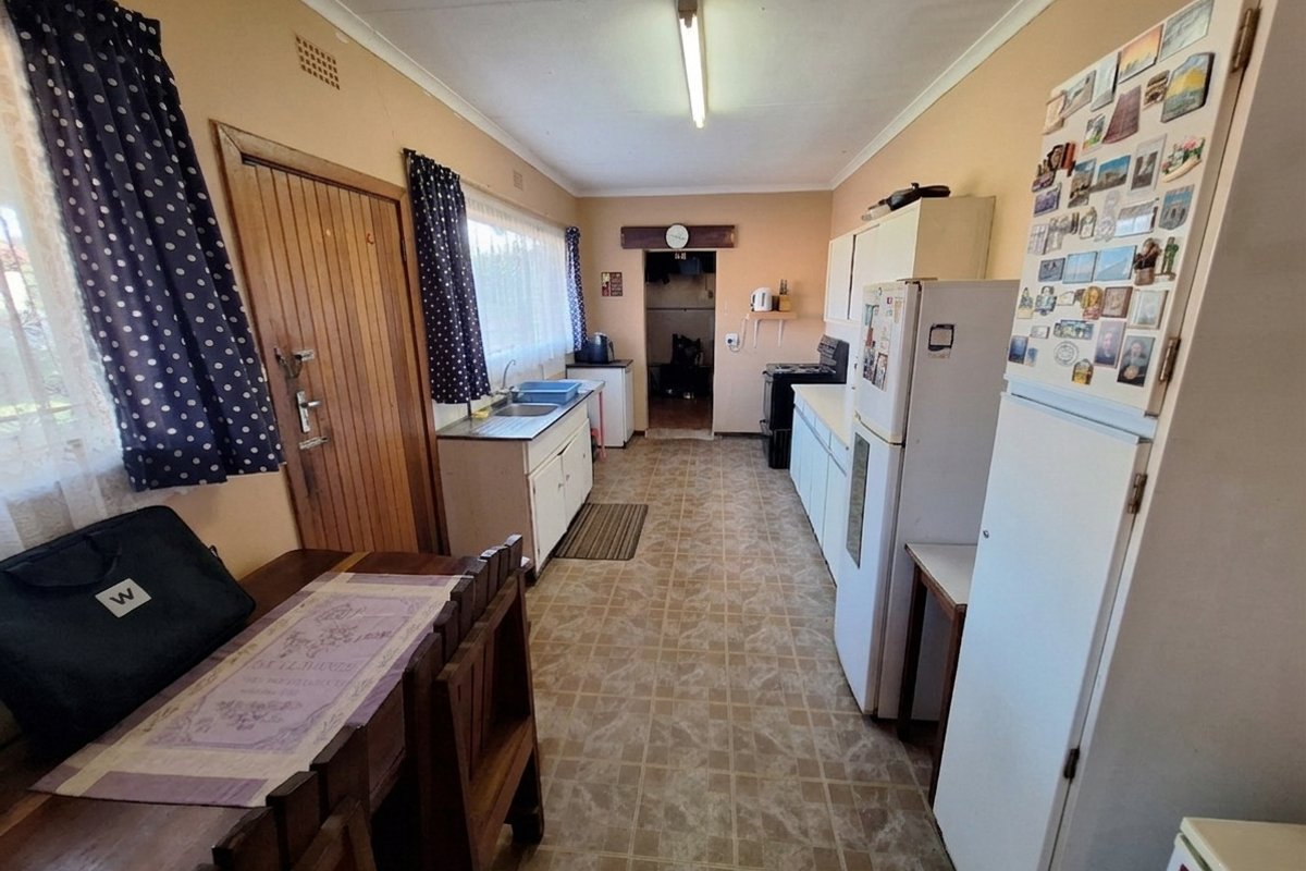 A functional kitchen featuring dated cabinetry, vinyl flooring, and a built-in sink, offering potential for modernization and aesthetic updates.