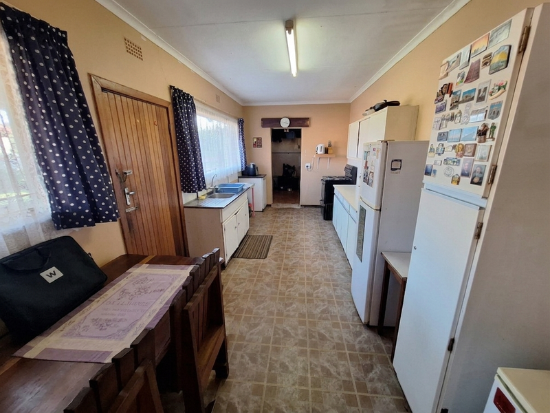 A functional kitchen featuring dated cabinetry, vinyl flooring, and a built-in sink, offering potential for modernization and aesthetic updates.