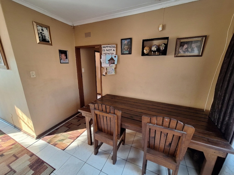 A dining area featuring tiled flooring and coved ceilings, currently showing signs of wear on the wall surfaces.