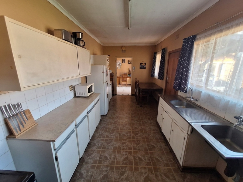 A functional kitchen featuring built-in cabinetry, double stainless steel sinks, and tiled backsplashes, offering a dated layout ready for modernization.