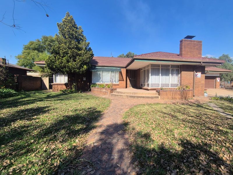 Front view of a single-story brick house featuring a tiled roof, brick chimney, paved walkway, and a raised patio area.