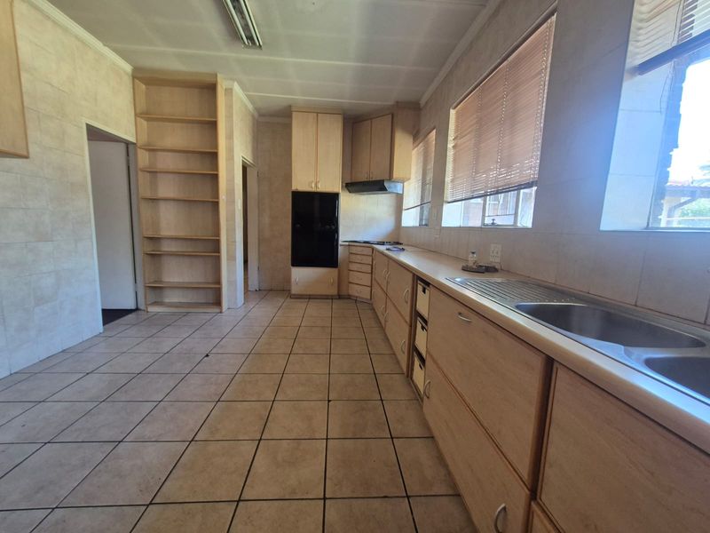 A spacious, functional kitchen featuring extensive built-in cabinetry, a double bowl sink, built-in oven, and tiled finishes throughout.