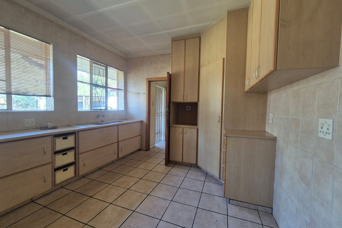 A functional, empty kitchen featuring extensive built-in cabinetry, tiled flooring, and tiled walls, offering a blank canvas for modern renovation.