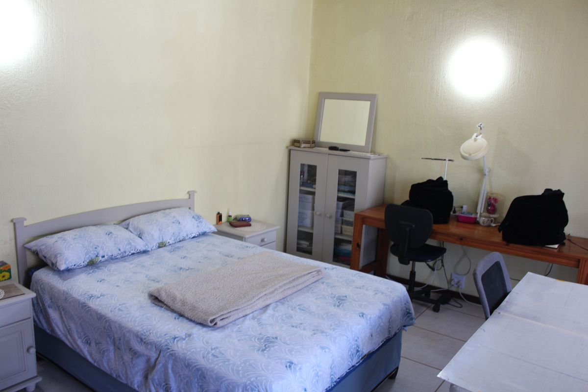 A functional bedroom featuring tiled flooring and neutral wall finishes, providing a practical space for rest and study.