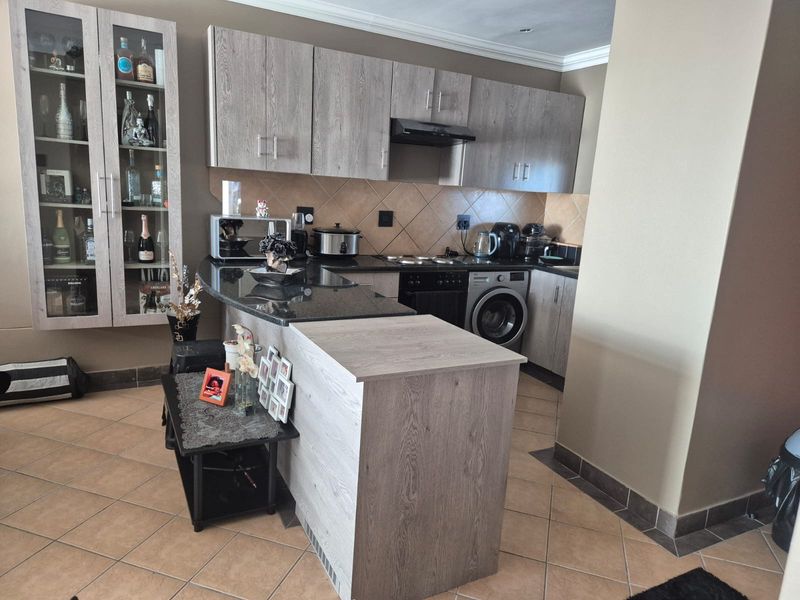 A functional kitchen featuring wood-look cabinetry, granite countertops, a built-in oven with extractor fan, and an integrated washing machine.