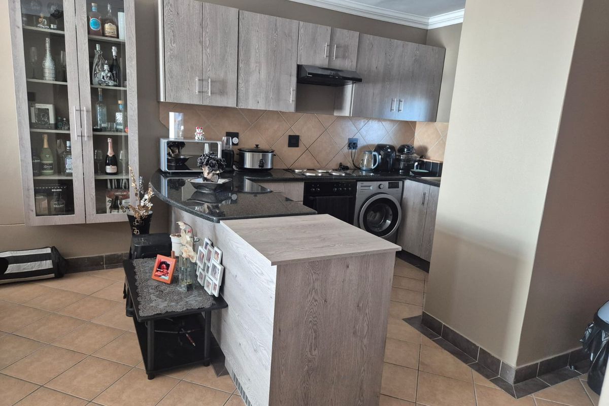 A functional kitchen featuring wood-look cabinetry, granite countertops, a built-in oven with extractor fan, and an integrated washing machine.