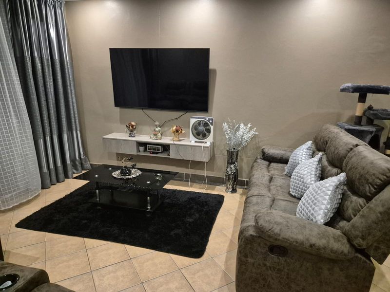 A comfortable living room featuring tiled flooring and a wall-mounted media console, providing a functional space for relaxation and entertainment.