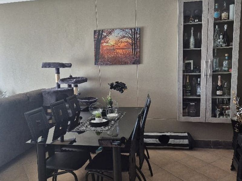 A dining area featuring tiled flooring, recessed downlighting, and a built-in wall-mounted display cabinet.
