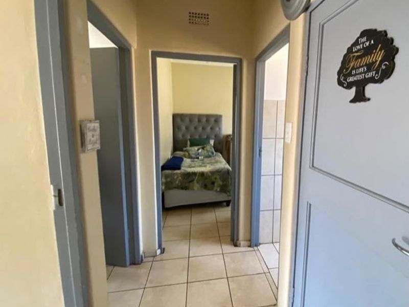 A functional hallway with tiled flooring providing access to adjacent rooms, including a bedroom visible at the end of the corridor.