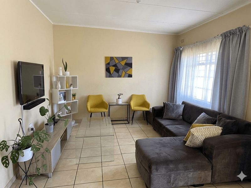 A comfortable living room featuring neutral tiled flooring and a large window that allows for natural light.