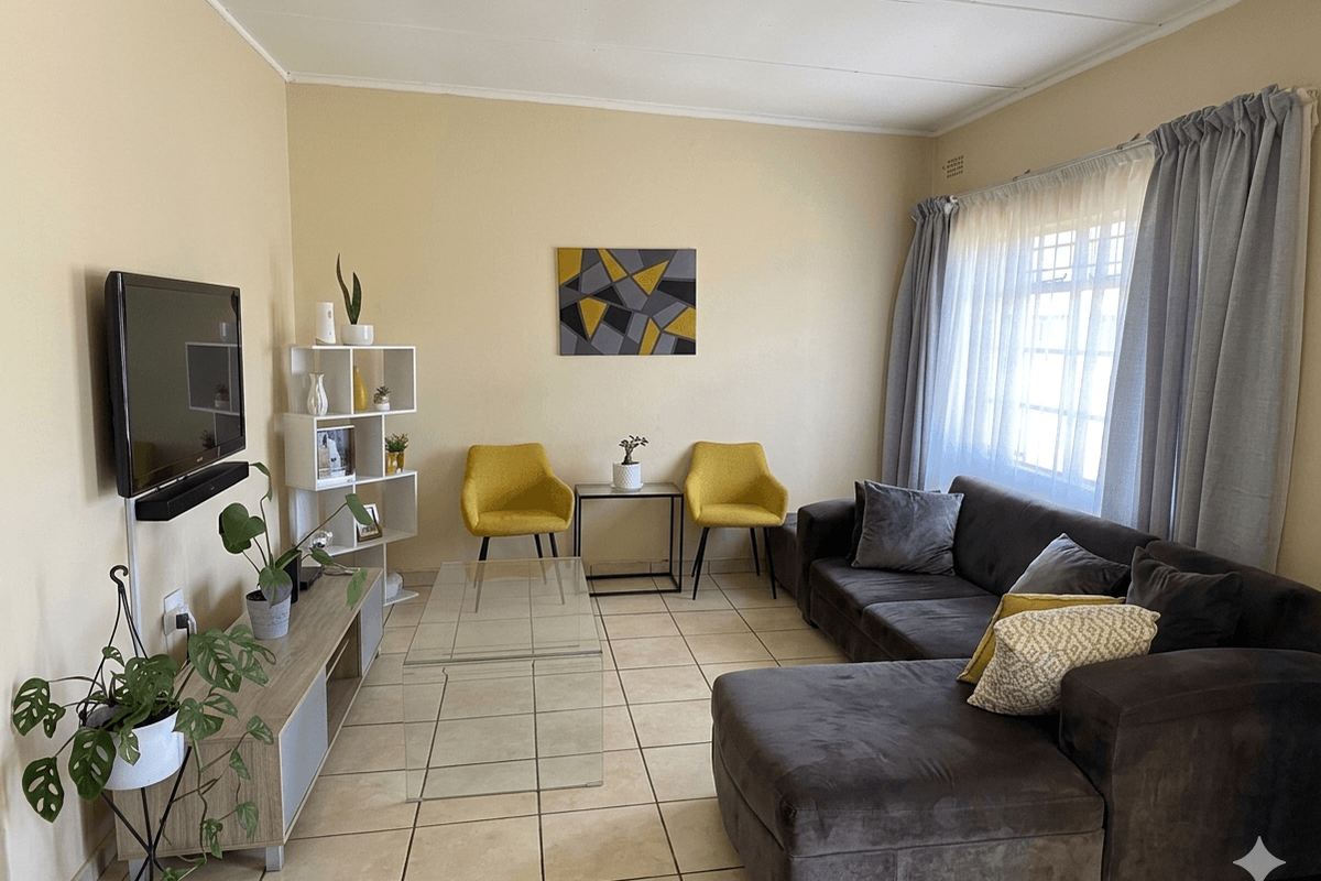 A comfortable living room featuring neutral tiled flooring and a large window that allows for natural light.