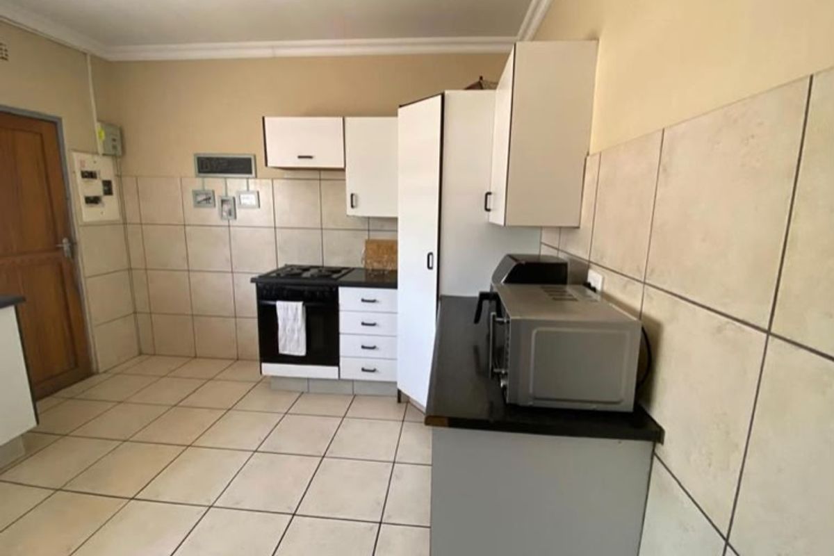 A functional kitchen featuring tiled flooring, tiled splashbacks, built-in cabinetry, and a gas hob with an integrated oven.