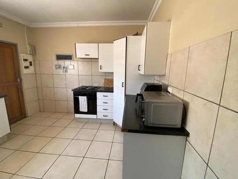 A functional kitchen featuring tiled flooring, tiled splashbacks, built-in cabinetry, and a gas hob with an integrated oven.