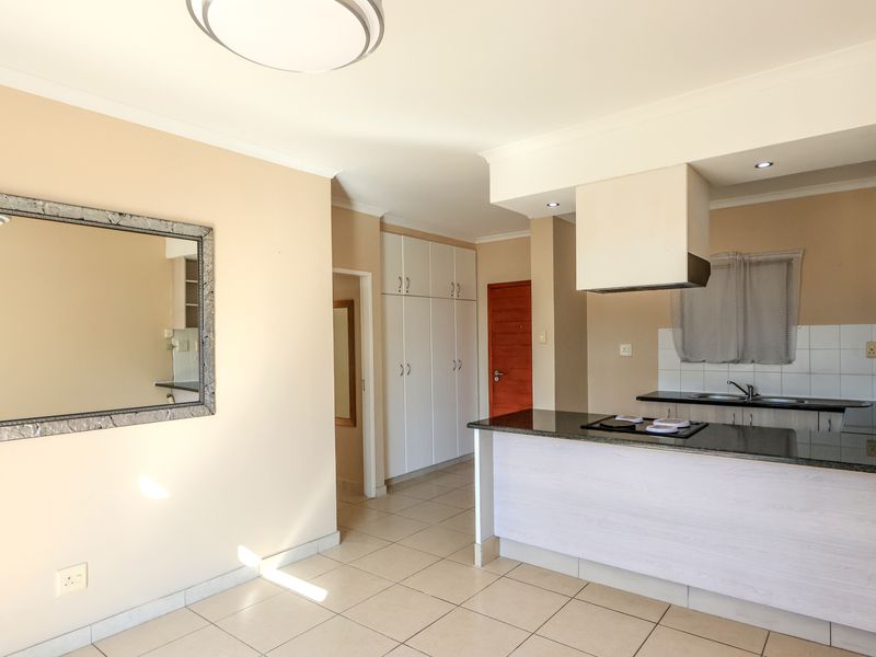 Open-plan kitchen and living area featuring granite countertops, built-in cabinetry, and tiled flooring in a well-maintained apartment setting.