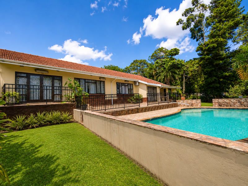 Rear exterior view featuring a swimming pool with tiled coping, a paved terrace area, and direct access to the house via sliding glass doors.