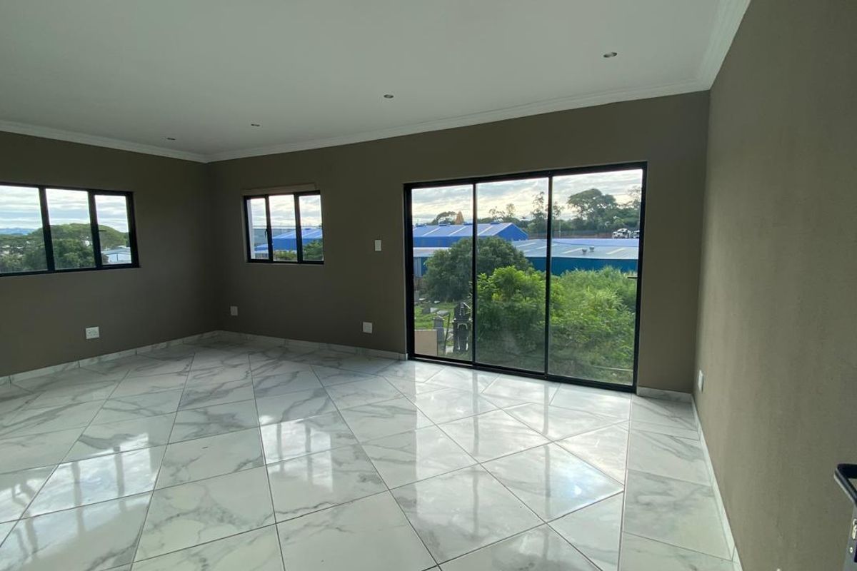 Spacious, empty living area featuring polished marble-look floor tiles, recessed lighting, and large sliding glass doors providing natural light and outdoor access.