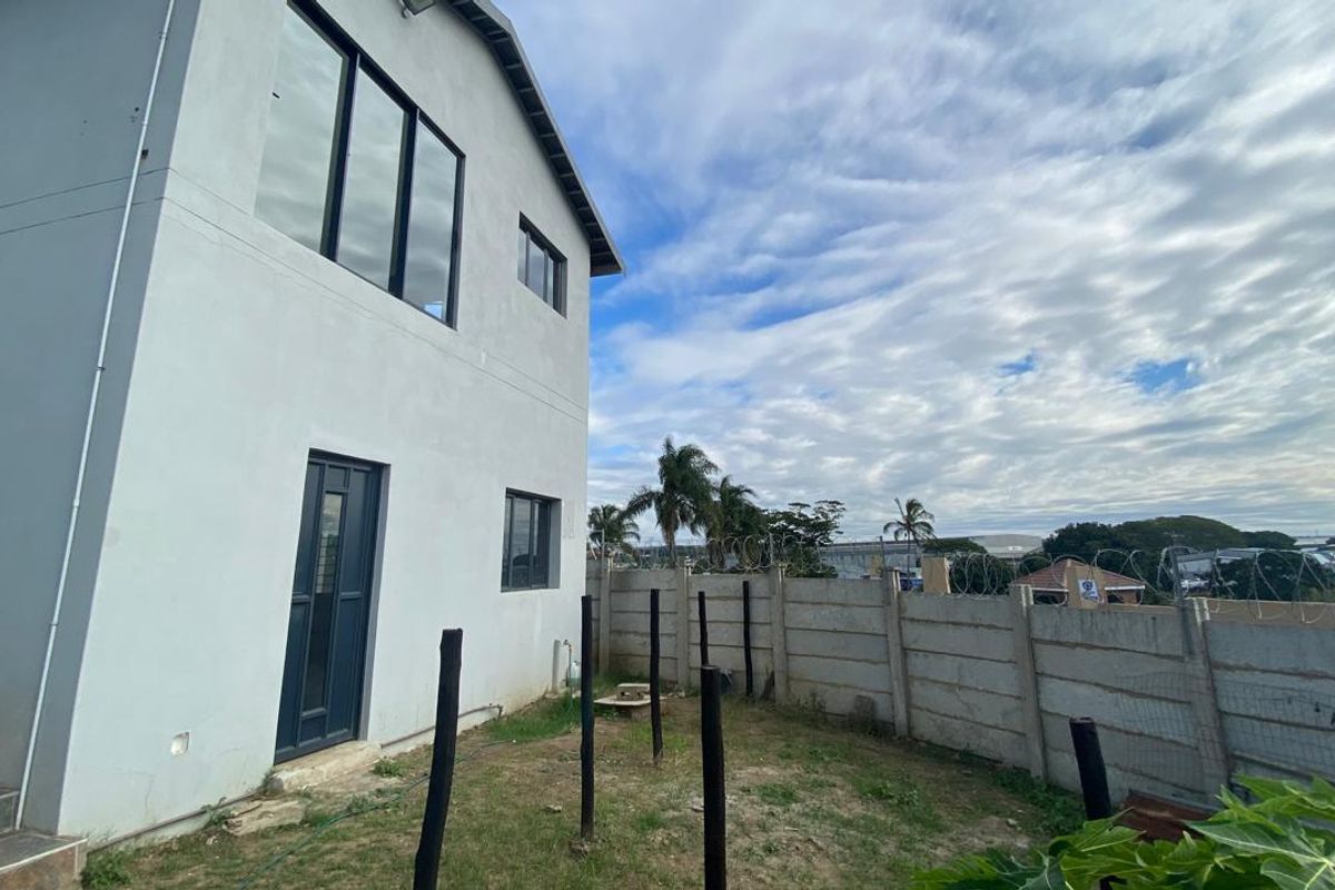 Rear exterior view of the property featuring a precast concrete boundary wall with security razor wire and an external tiled staircase.
