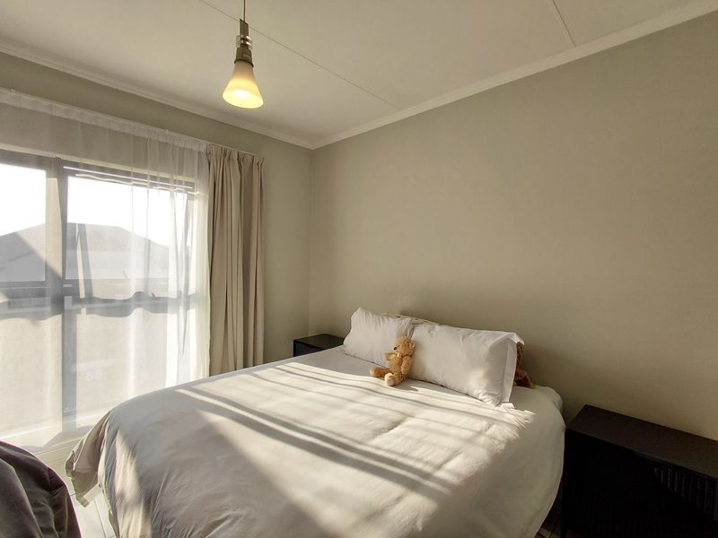 A bright bedroom featuring a large window with natural light and a central ceiling light fixture.