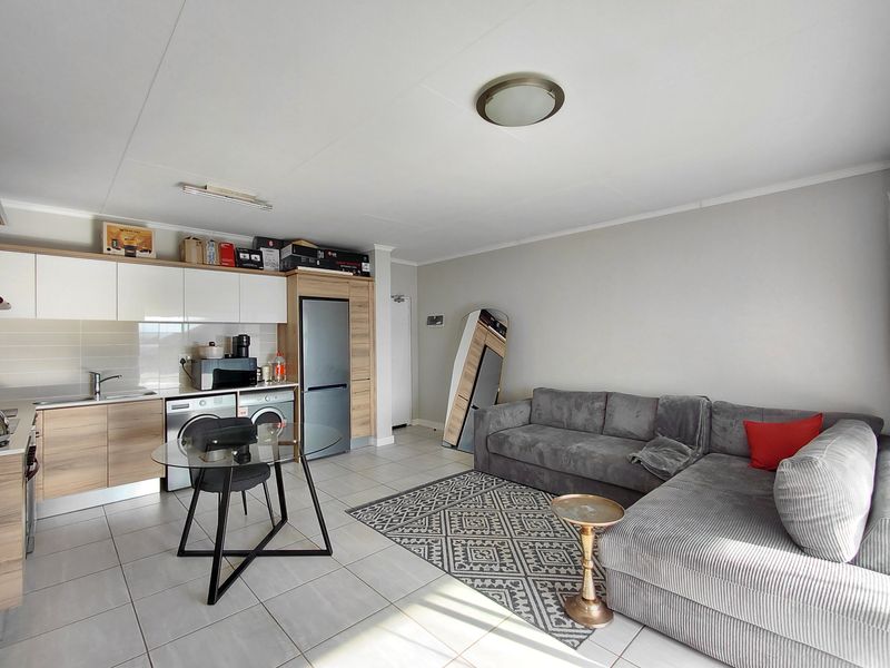 Modern open-plan living area featuring a contemporary kitchen with built-in cabinetry, tiled flooring, and a seamless transition to the lounge space.