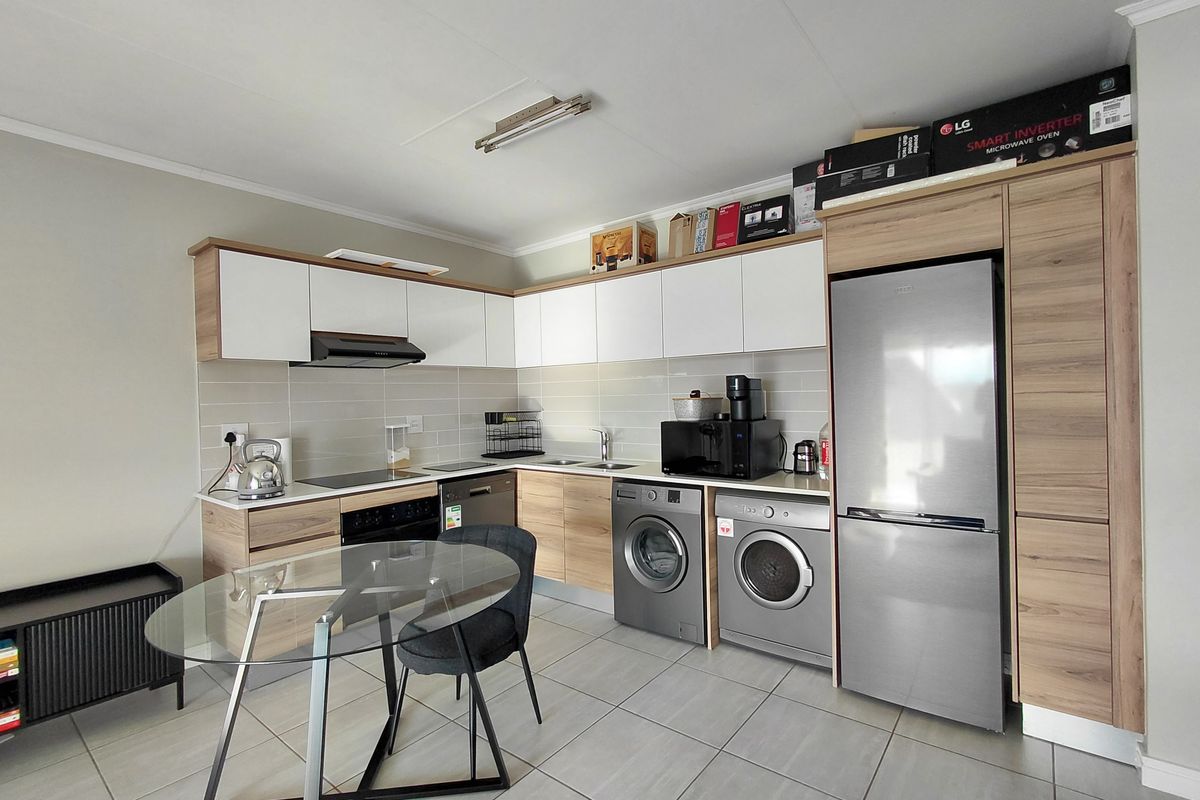 Modern kitchen featuring light wood and white cabinetry, tiled backsplash, integrated appliance spaces, and durable tiled flooring in a clean, functional layout.