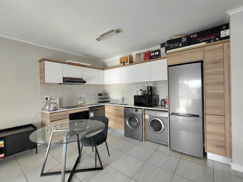 Modern kitchen featuring light wood and white cabinetry, tiled backsplash, integrated appliance spaces, and durable tiled flooring in a clean, functional layout.