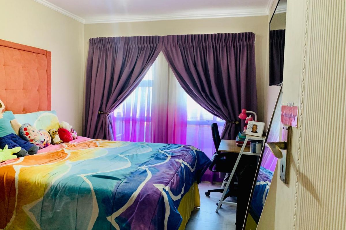 A functional bedroom featuring tiled flooring, a built-in headboard, and window treatments, providing a comfortable and practical living space.