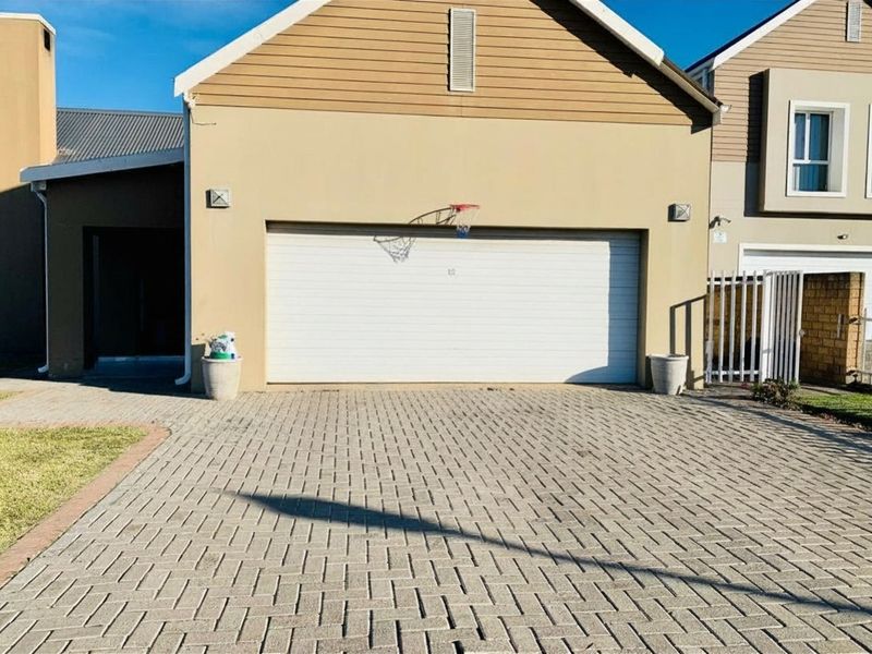 A well-maintained double garage with a paved driveway and exterior lighting, featuring a clean facade and secure gated access.