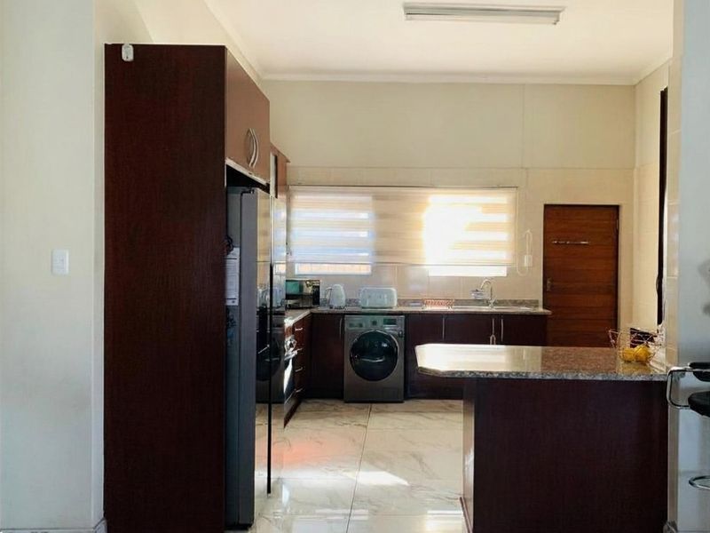 A functional kitchen featuring dark wood cabinetry, granite countertops, marble-look floor tiles, and a convenient breakfast bar for casual dining.