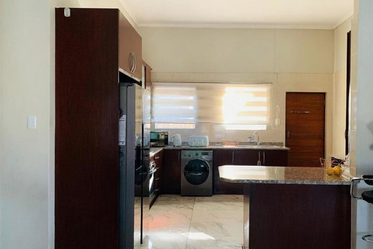 A functional kitchen featuring dark wood cabinetry, granite countertops, marble-look floor tiles, and a convenient breakfast bar for casual dining.
