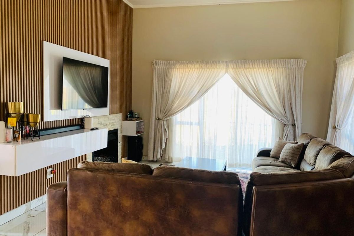 A well-maintained living room featuring a modern slatted wood accent wall, a built-in fireplace, and large sliding doors providing natural light.
