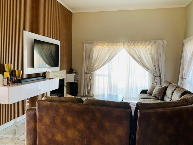 A well-maintained living room featuring a modern slatted wood accent wall, a built-in fireplace, and large sliding doors providing natural light.