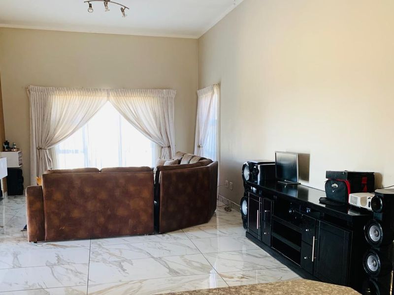 Spacious living room featuring polished marble-look floor tiles, neutral walls, and large sliding glass doors that provide ample natural light.