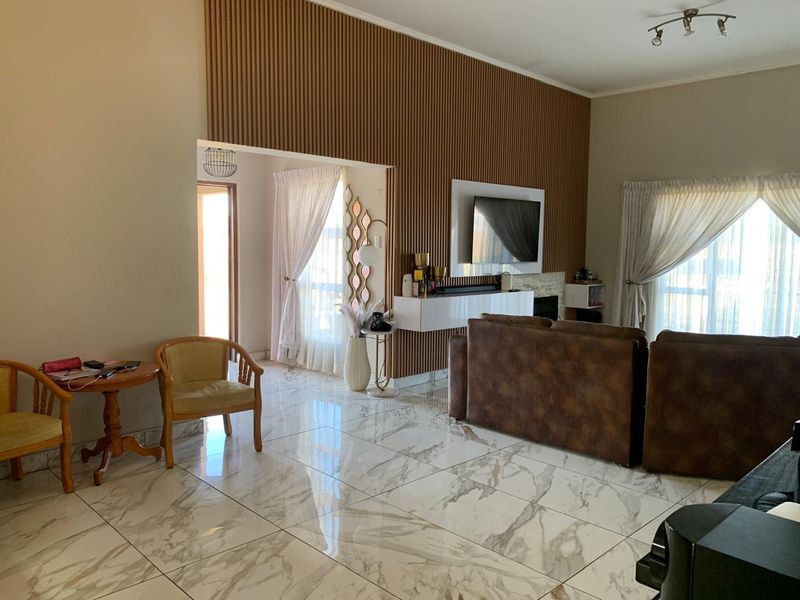 Spacious living room featuring modern marble-look floor tiles, a striking floor-to-ceiling slatted timber feature wall, and a built-in floating media console.
