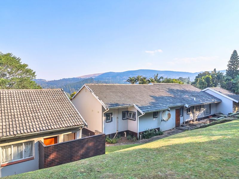 Rear view of the property featuring a tiled roof, brick wall construction, and casement windows, set against a scenic mountain landscape.