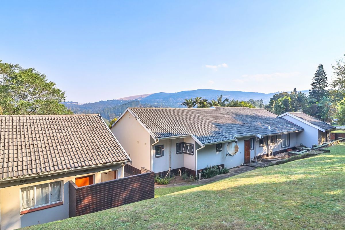 Rear view of the property featuring a tiled roof, brick wall construction, and casement windows, set against a scenic mountain landscape.