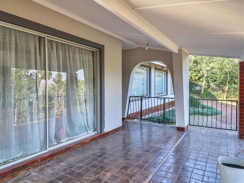 A covered outdoor patio featuring tiled flooring, arched architectural details, and a metal balustrade, providing a functional space for outdoor relaxation.