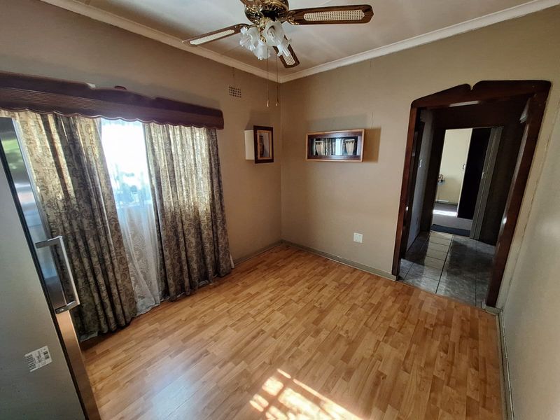 An empty living area featuring laminate flooring, a ceiling fan, and a classic arched doorway leading to an adjacent hallway.