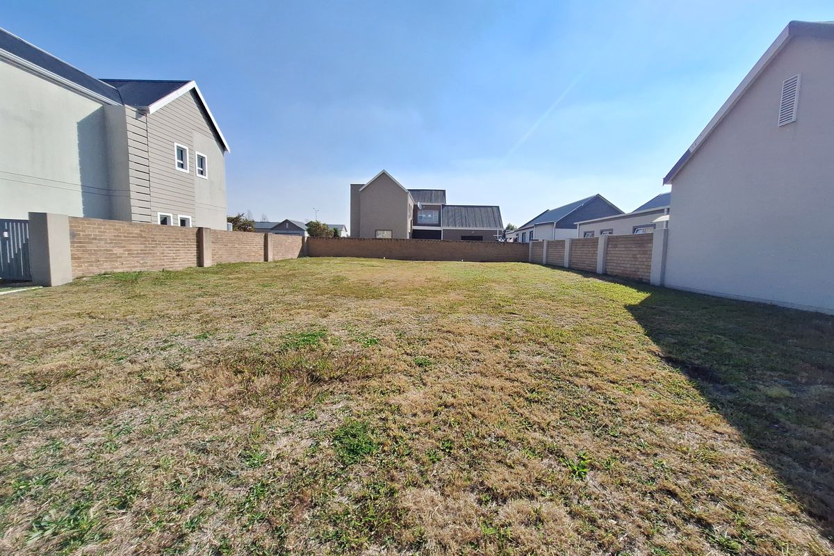 A vacant residential plot enclosed by perimeter brick walls, situated within a developed neighborhood setting.