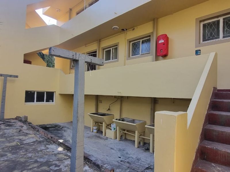 Rear exterior view of the apartment building featuring a communal laundry area with concrete wash troughs and an external staircase.