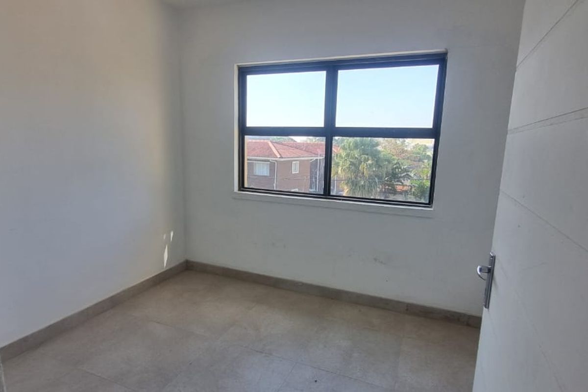 An empty bedroom featuring tiled flooring and an aluminium window frame, presenting a blank canvas ready for personalization.