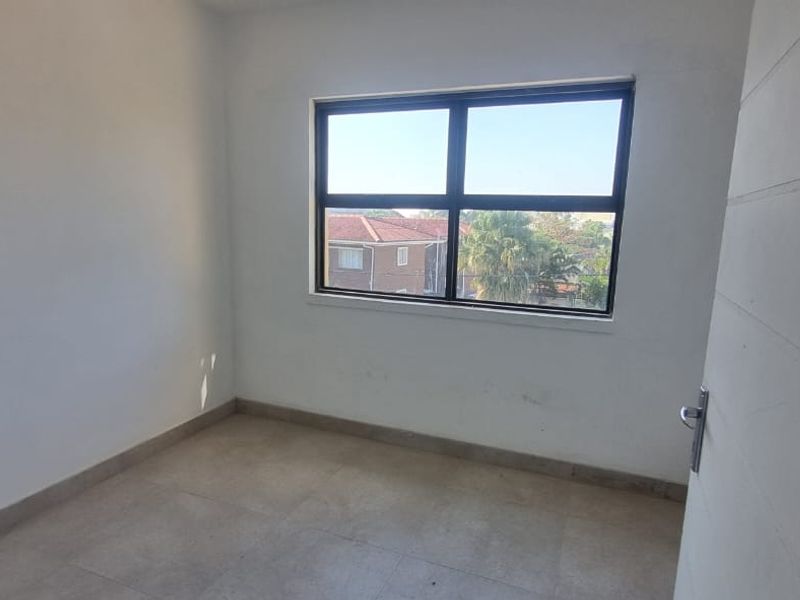 An empty bedroom featuring tiled flooring and an aluminium window frame, presenting a blank canvas ready for personalization.